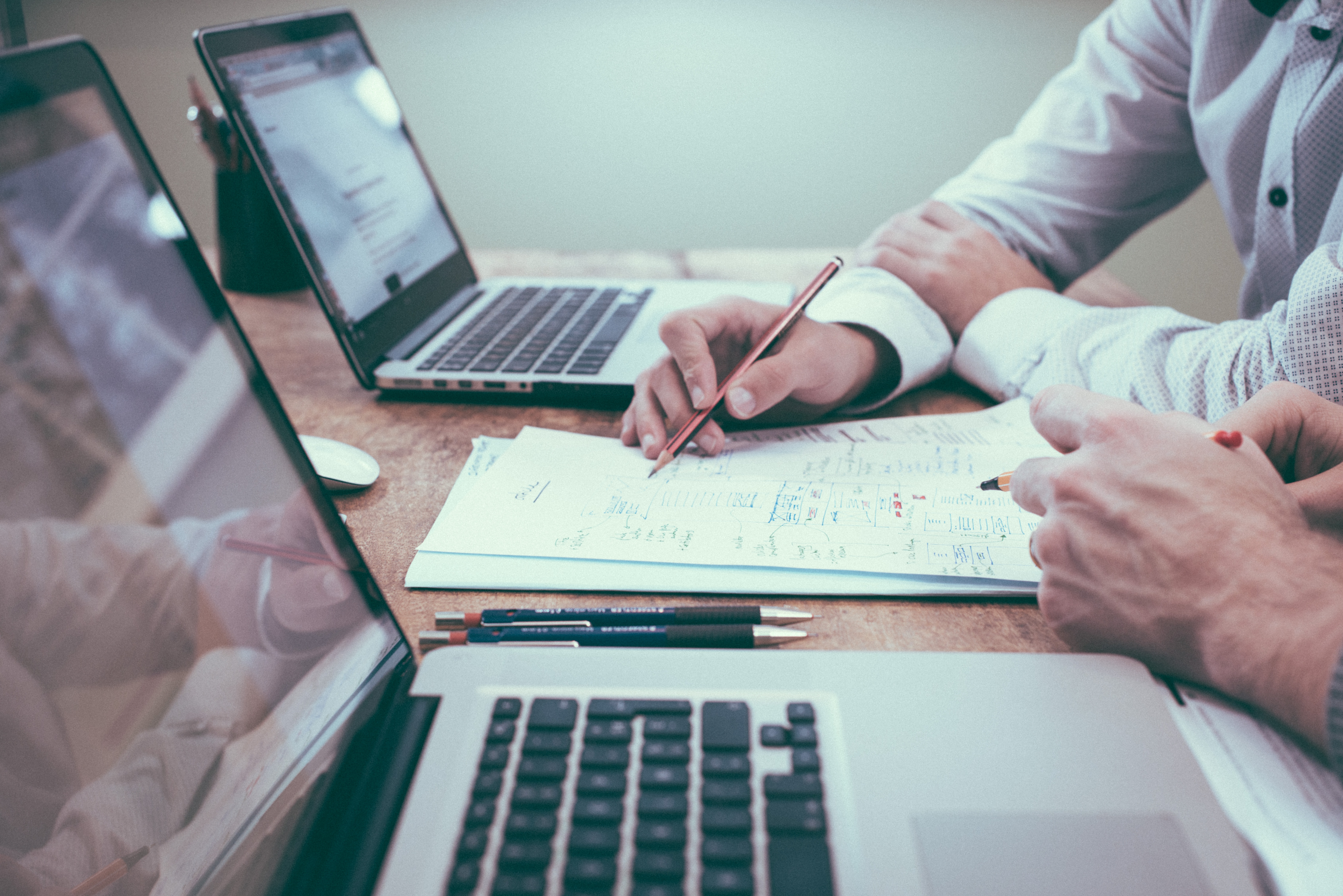 Zwei Personen arbeiten an Laptops und Papier