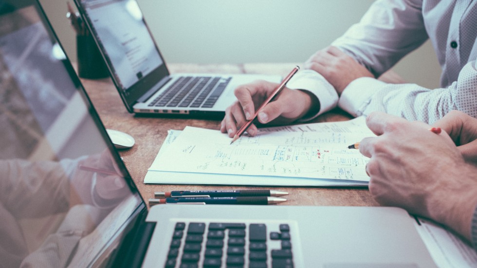 Zwei Personen arbeiten an Laptops und Papier